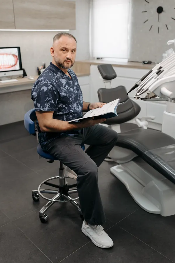 Dentist seated beside a dental chair in a modern clinic
