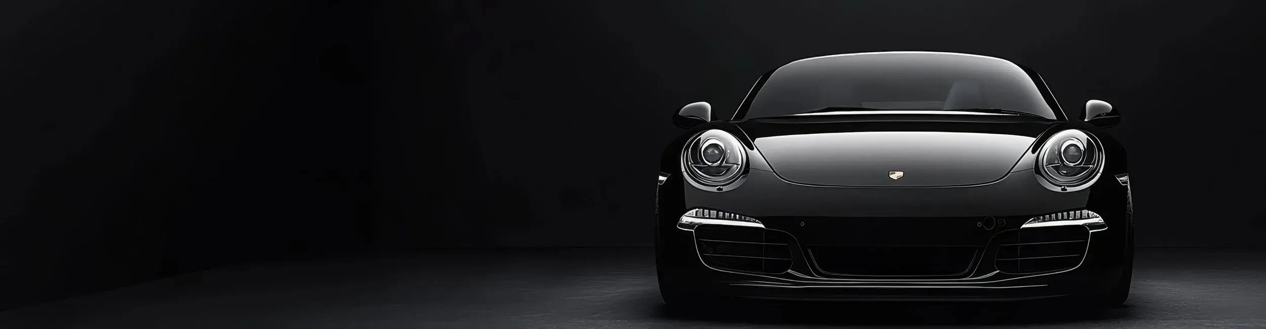 Black Porsche sports car illuminated against a dark studio background