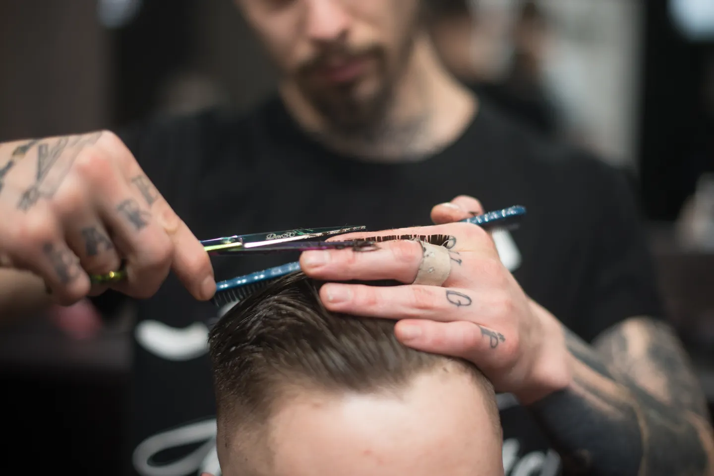 Close-up of a barber cutting hair with scissors and comb