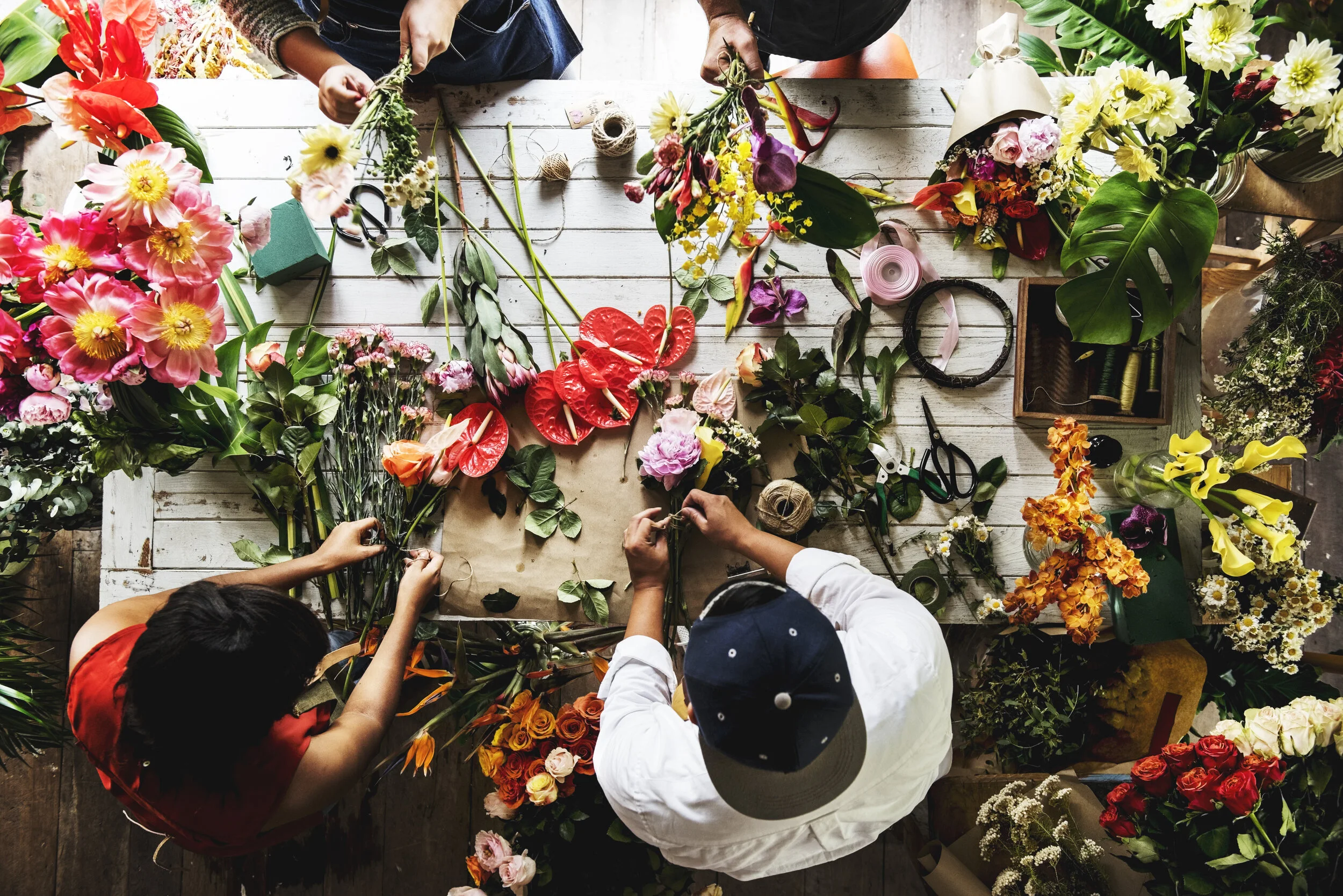 Florists arranging colourful stems around a busy studio worktable